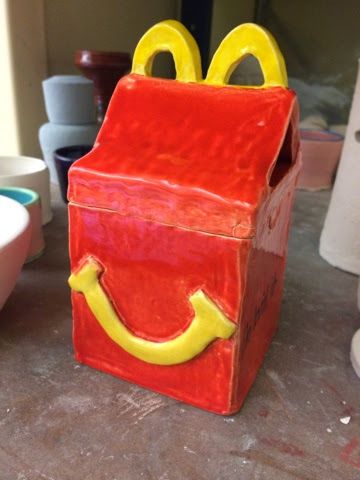 a red box with yellow handles that has a smiley face on it, sitting on a table