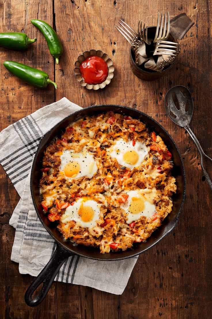 an iron skillet with eggs on top of it next to silverware and spoons