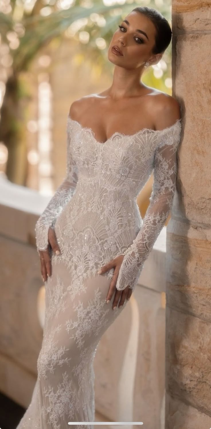 a woman in a wedding dress leaning against a wall