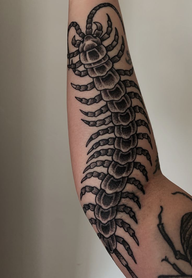 the arm is covered with black ink and has a scorch tattoo on it