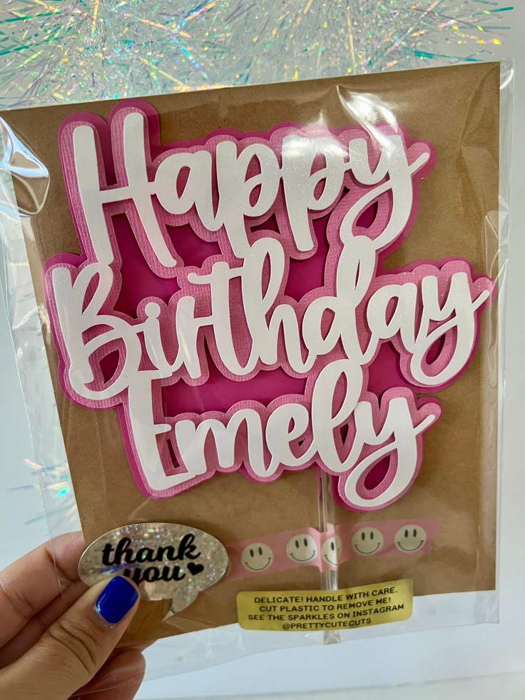 a hand holding up a happy birthday cake topper