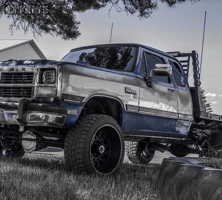 a large truck parked in the grass next to a tree