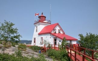 a red and white light house sitting on top of a hill