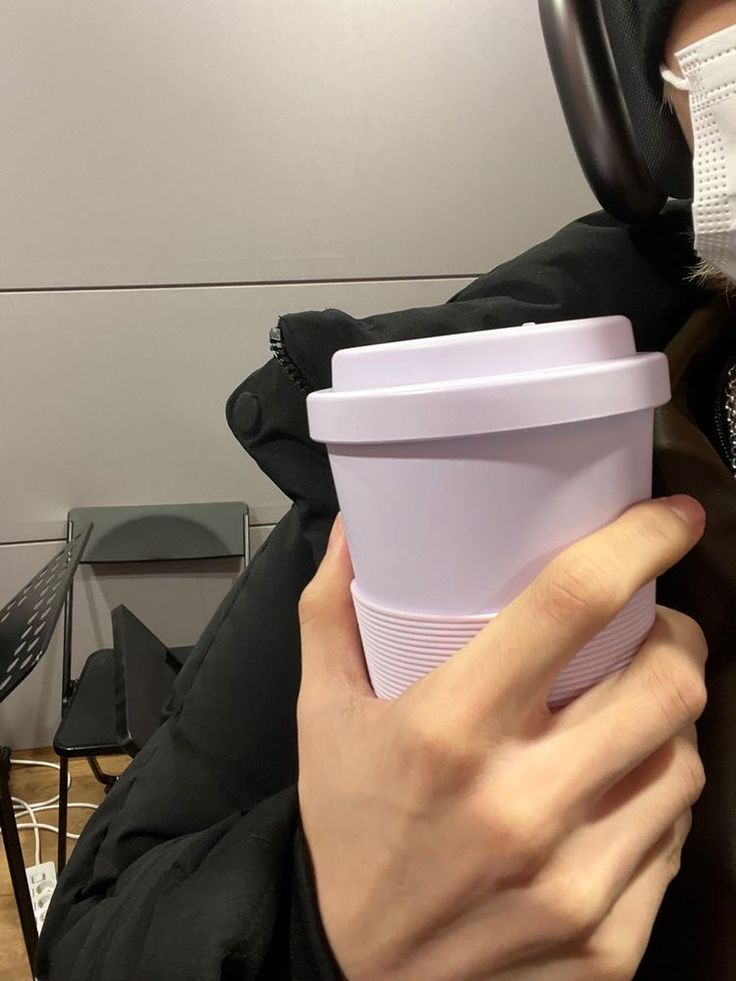 a person wearing a face mask and holding a cup