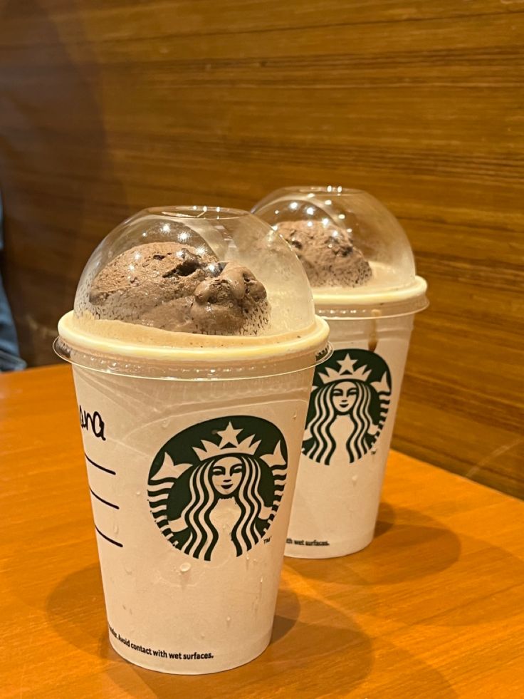 three starbucks drinks sitting on top of a wooden table