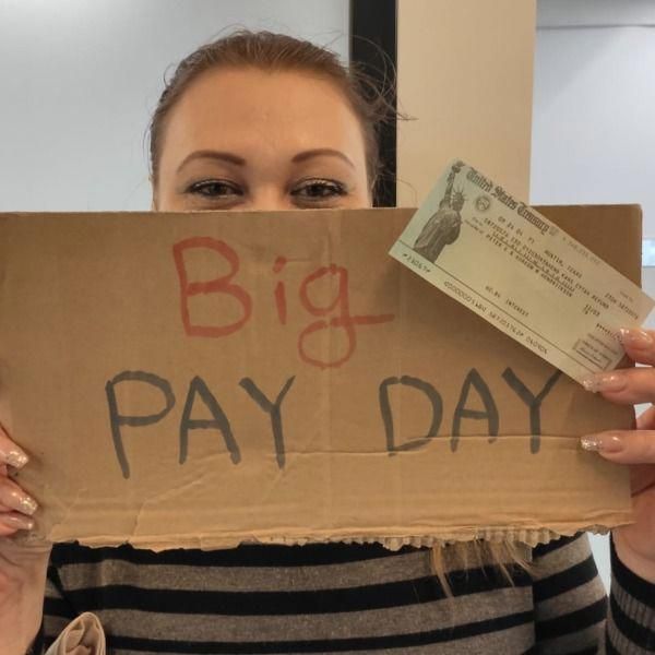 a woman holding up a cardboard sign that says,'big pay day'in front of her face