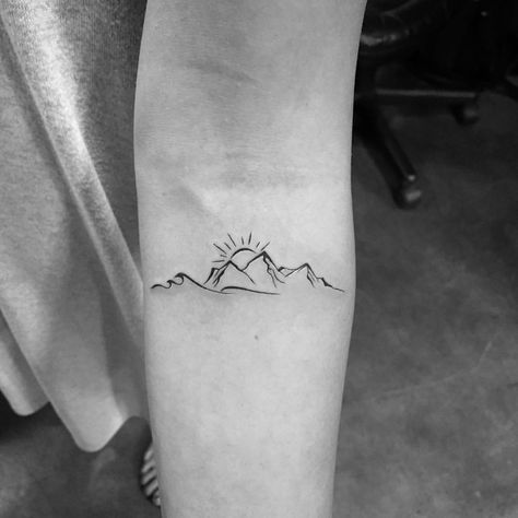 a black and white photo of a person's arm with a mountain tattoo on it