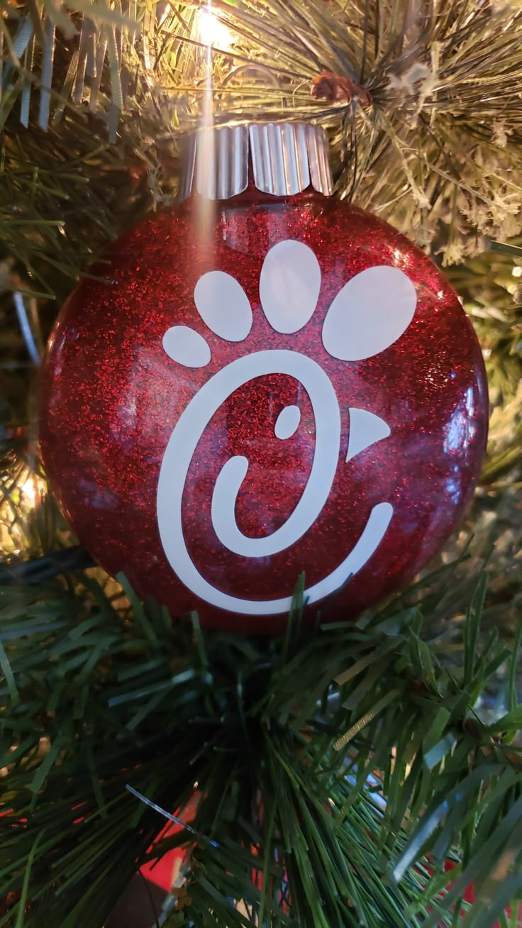 a red ornament hanging from a christmas tree with an animal paw on it