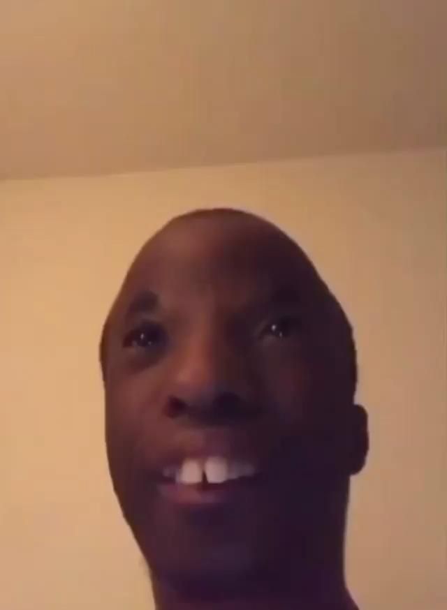 a man is smiling and looking up at the camera while wearing a red shirt with white teeth