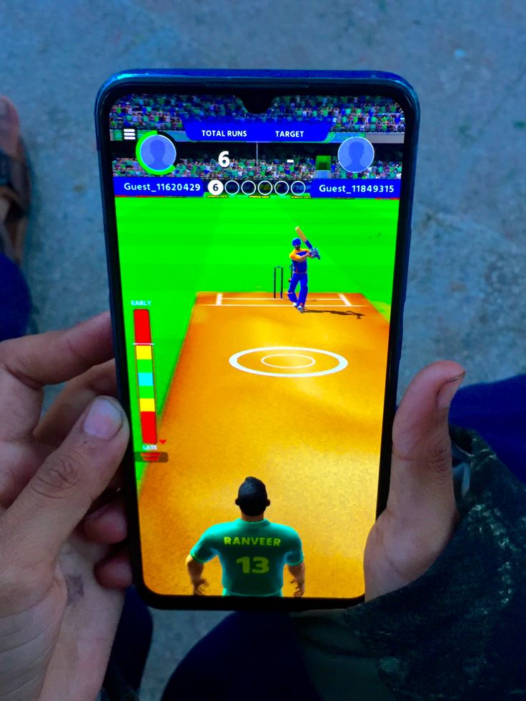 a person holding up a cell phone with a baseball game on the screen