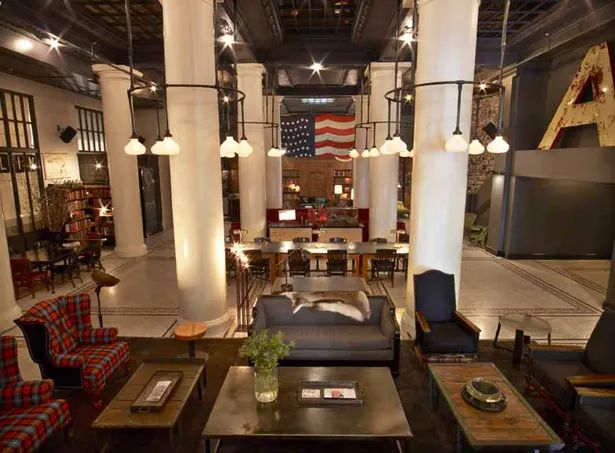 a large living room filled with lots of furniture and lighting fixture hanging from the ceiling