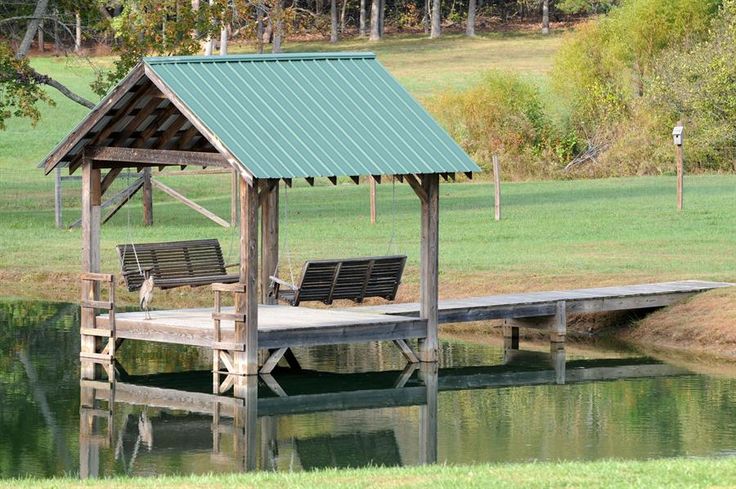 two benches sitting on a dock next to a body of water with a pavilion in the background