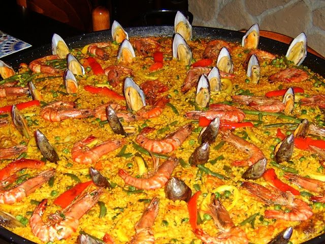 a large paella with shrimp, mussels and other seafood on it's side