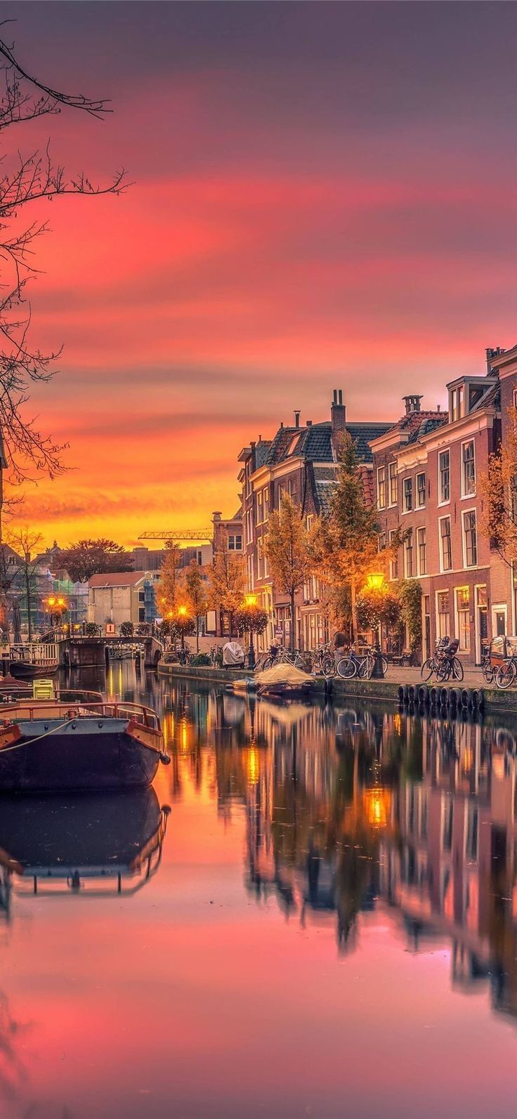 a boat is sitting in the water near some buildings and trees at sunset or dawn