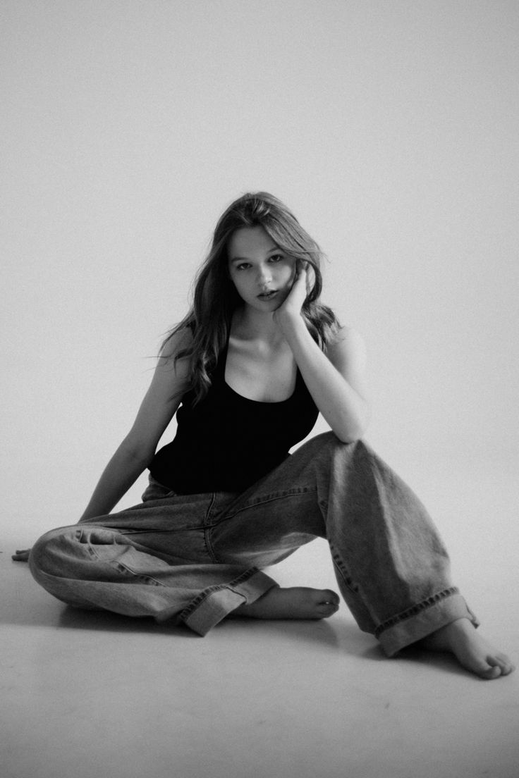 black and white photograph of a woman sitting on the floor with her hands to her face