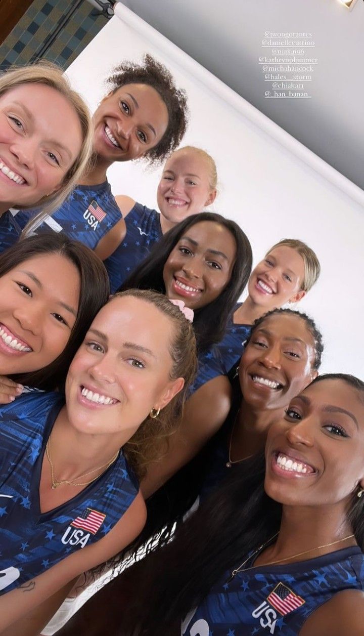 a group of women standing next to each other in front of a white wall with an american flag on it