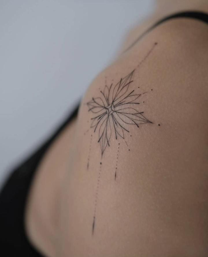 the back of a woman's shoulder with a flower tattoo on her left side