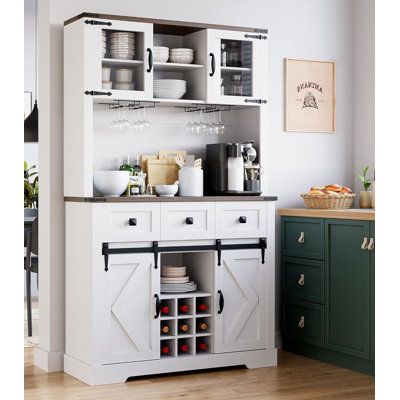 an open cabinet with wine glasses on it in a kitchen next to green cabinets and drawers