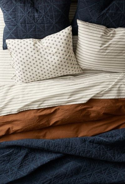 an unmade bed with blue and brown sheets