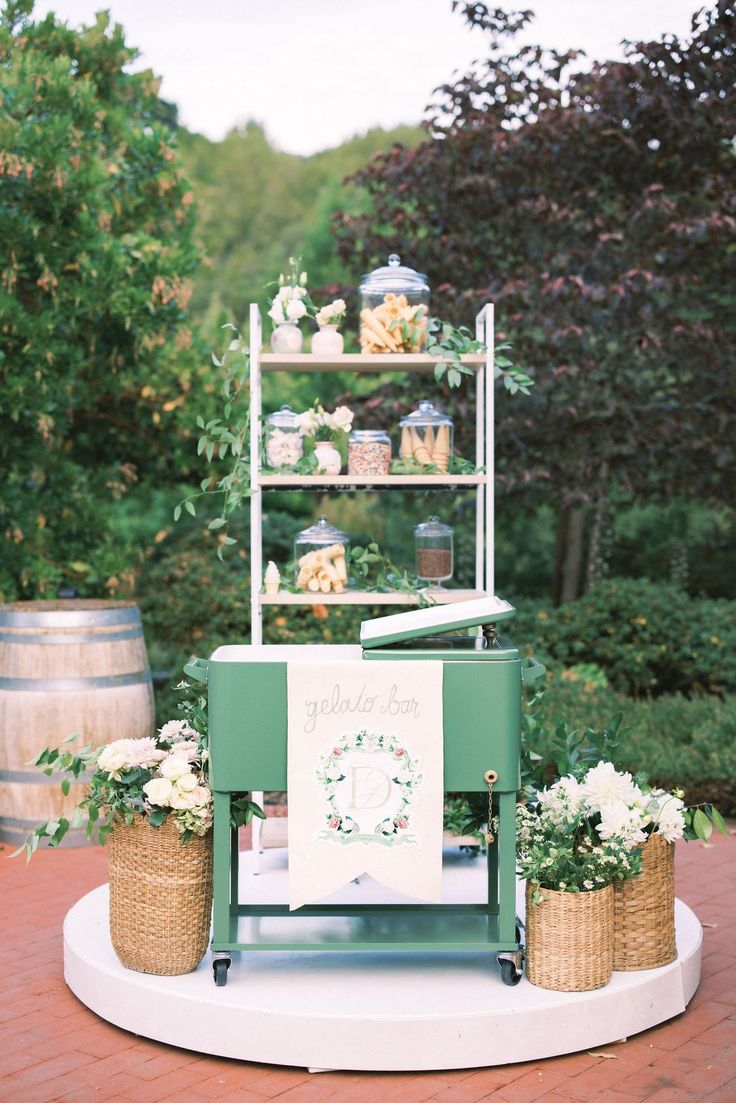 an ice cream cart is set up with flowers and greenery