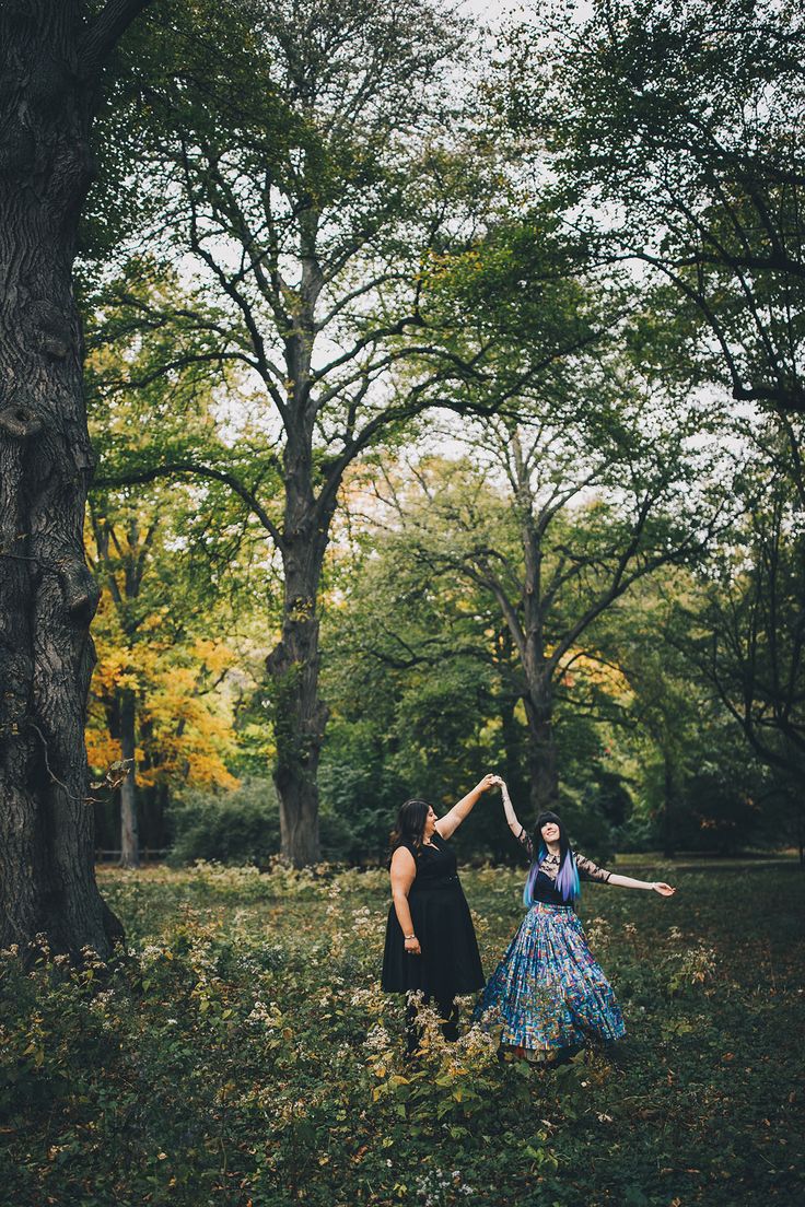 two women are dancing in the woods together