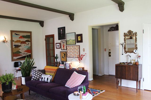 a living room filled with lots of furniture and pictures on the wall above it's doorway