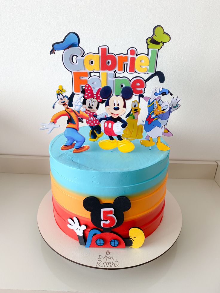 a mickey mouse birthday cake with colorful frosting and fondant decorations on the top