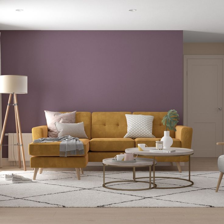 a living room with purple walls and white rugs on the floor, two yellow couches in front of a coffee table