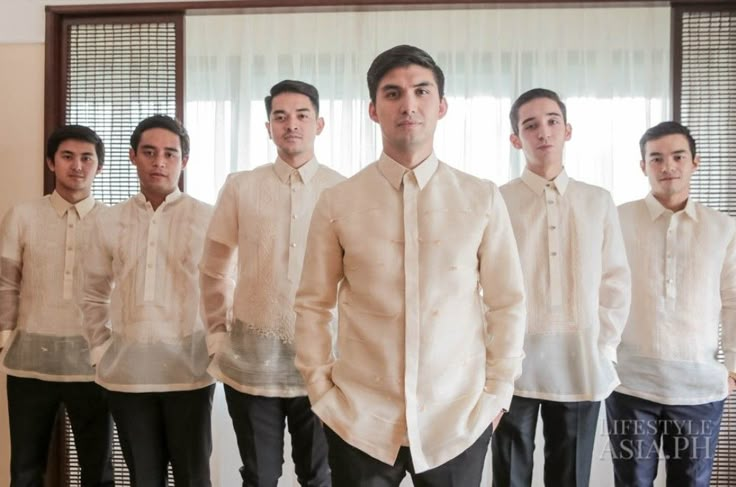 a group of young men standing next to each other in front of a window with blinds