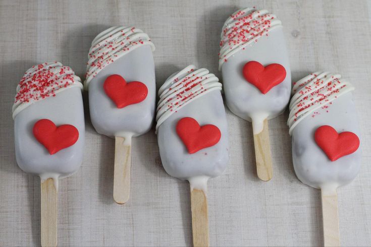 four pops with hearts on them sitting on a table