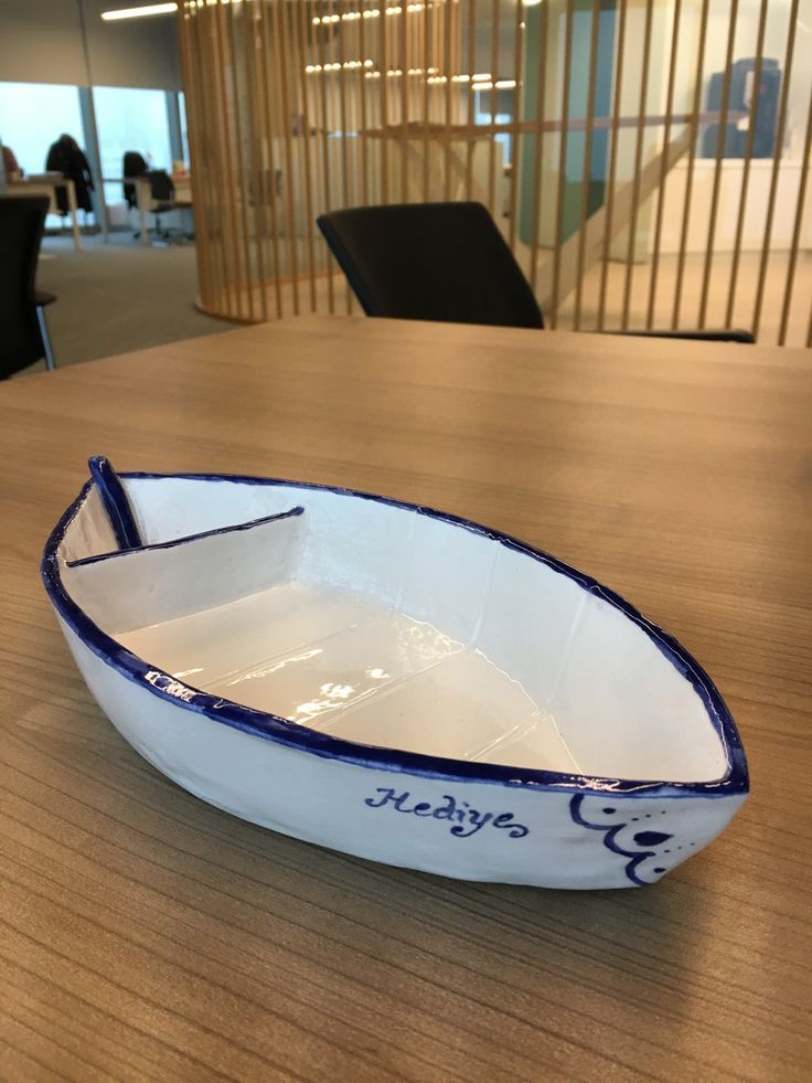 a white and blue boat sitting on top of a wooden table in an office building