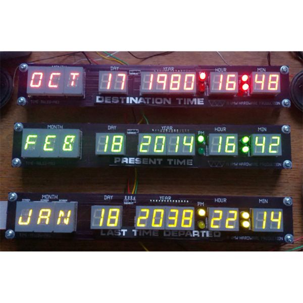 three electronic clocks sitting on top of a wooden table next to wires and plugged in