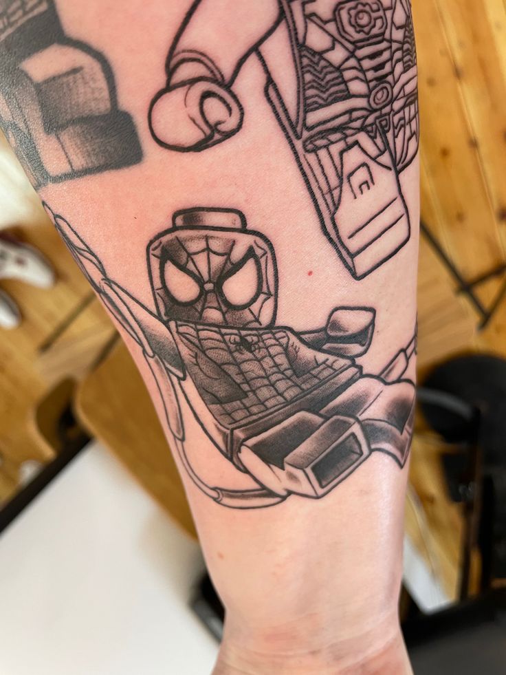 a person with a spiderman tattoo on their arm and hand, holding a lego figure