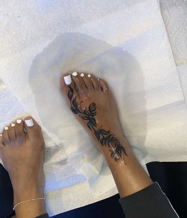 a woman's feet with black and white tattoos on them