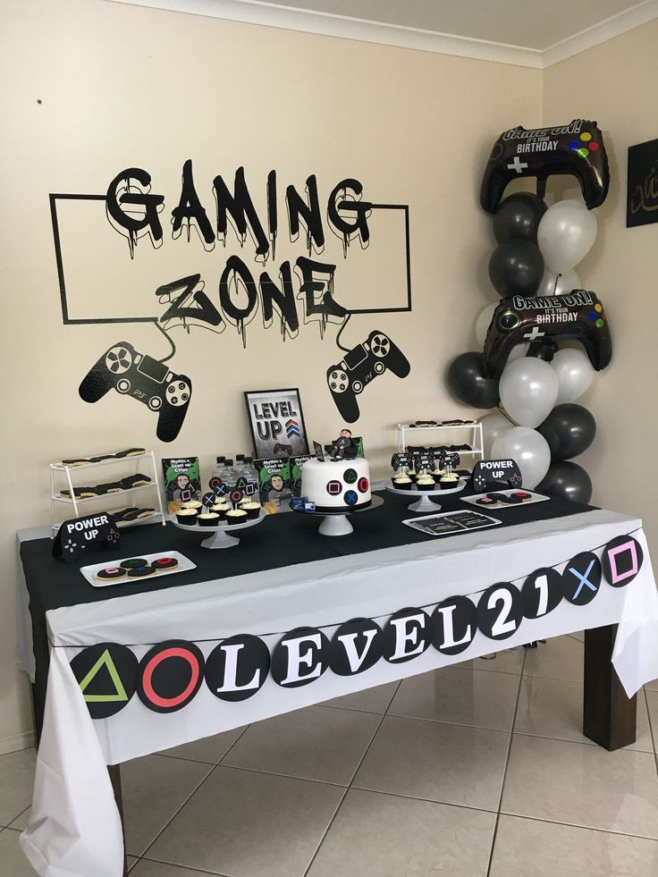 a gaming zone themed party table with balloons and streamers on the wall behind it