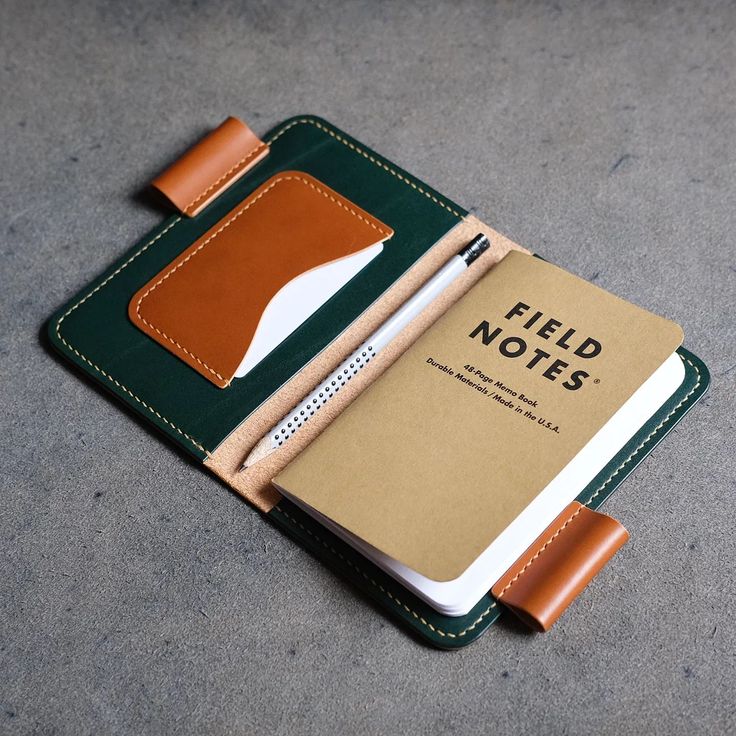 an open notebook with a notepad and pen in the pocket on top of it