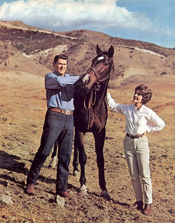 two people standing next to a horse in the desert