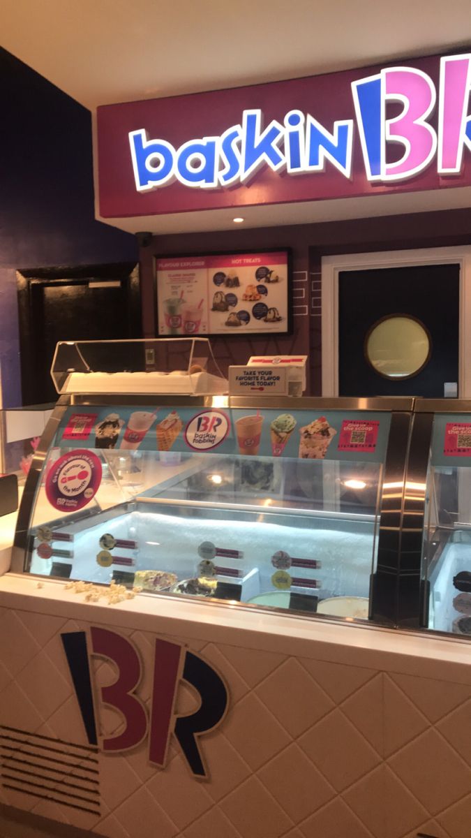 the inside of a fast food restaurant with an ice cream display case and neon sign