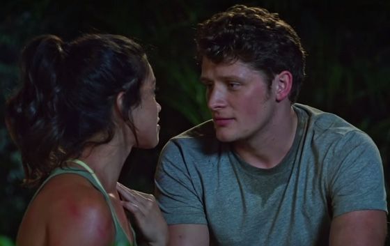 a young man and woman sitting next to each other in front of a dark background