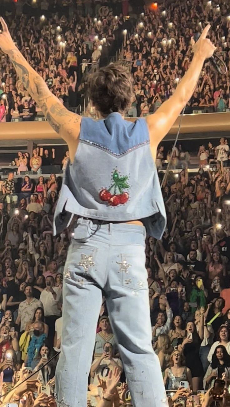 a person standing on top of a stage with their arms in the air and hands raised