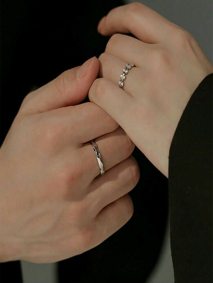 two people holding each other's hands with their wedding rings on top of them