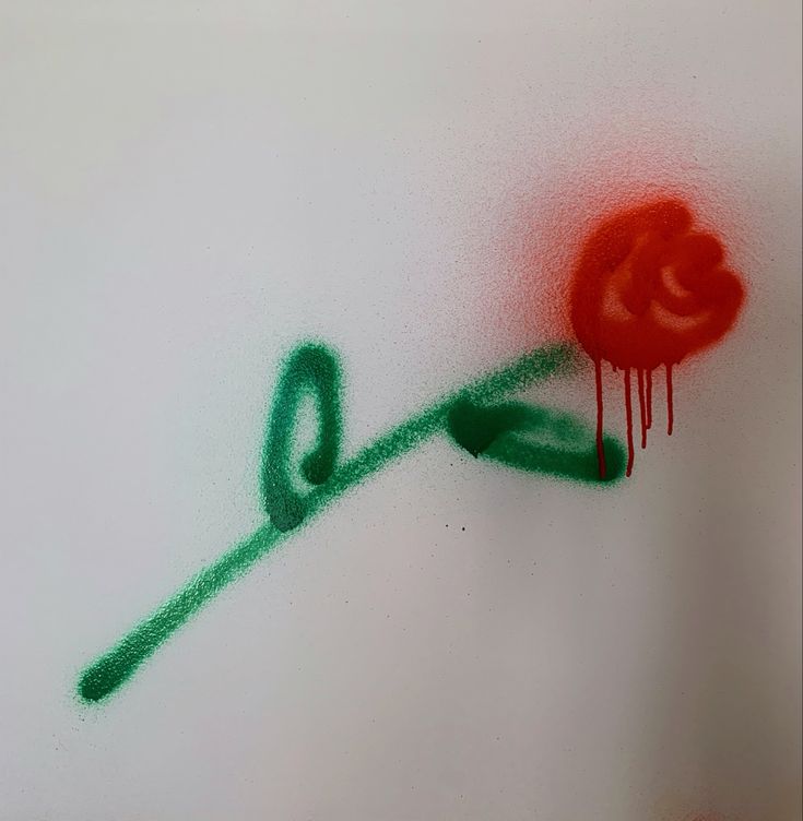 a red rose is drawn on the side of a white wall with green spray paint