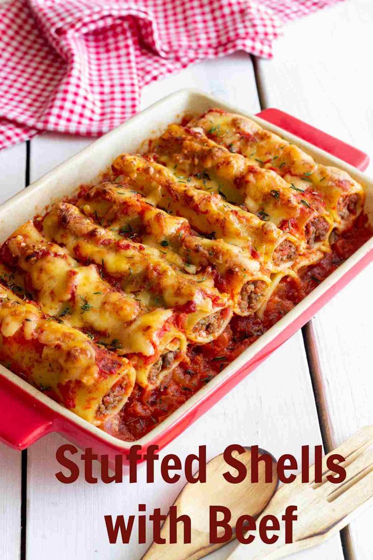 stuffed shells with beef in a red casserole dish on a white wooden table