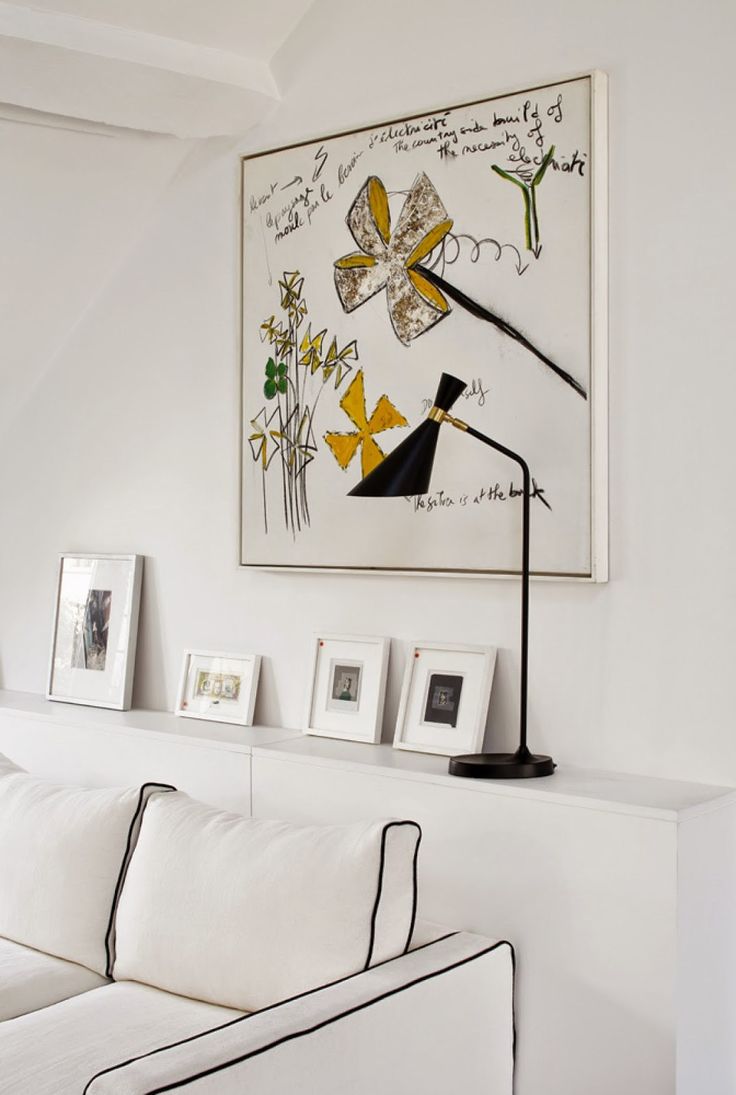 a living room with a white couch, black lamp and pictures hanging on the wall