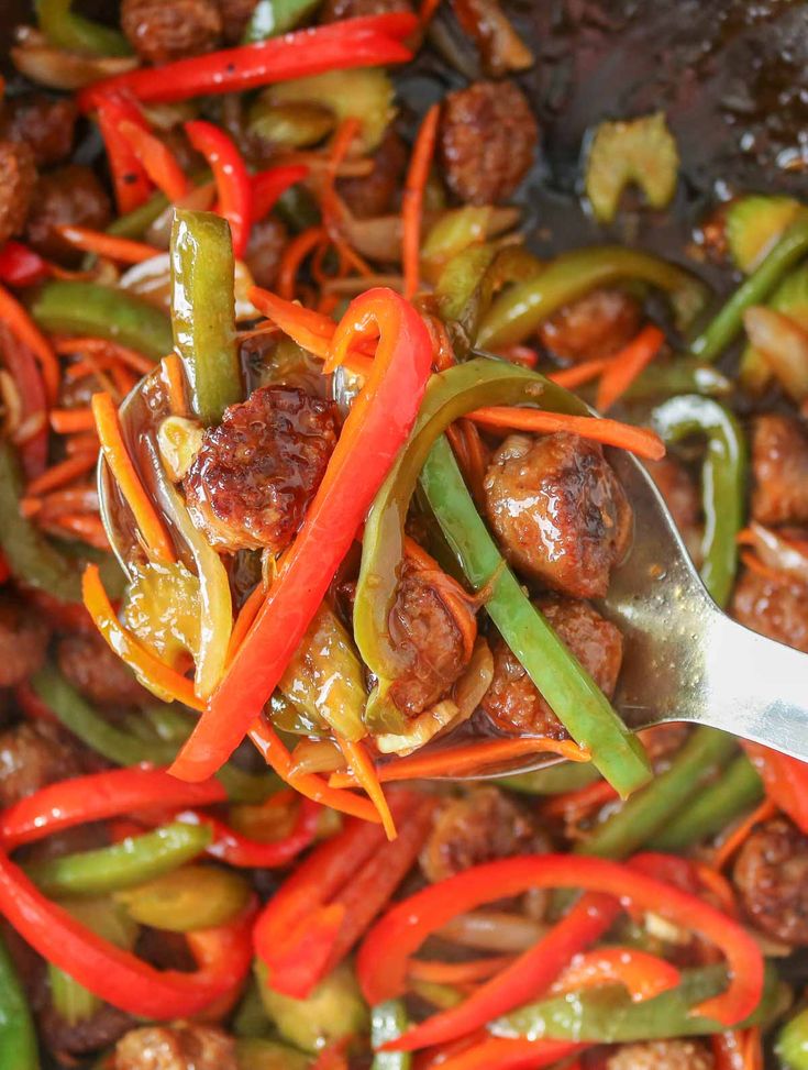 sausage and peppers being cooked in a skillet with a spatula to stir them