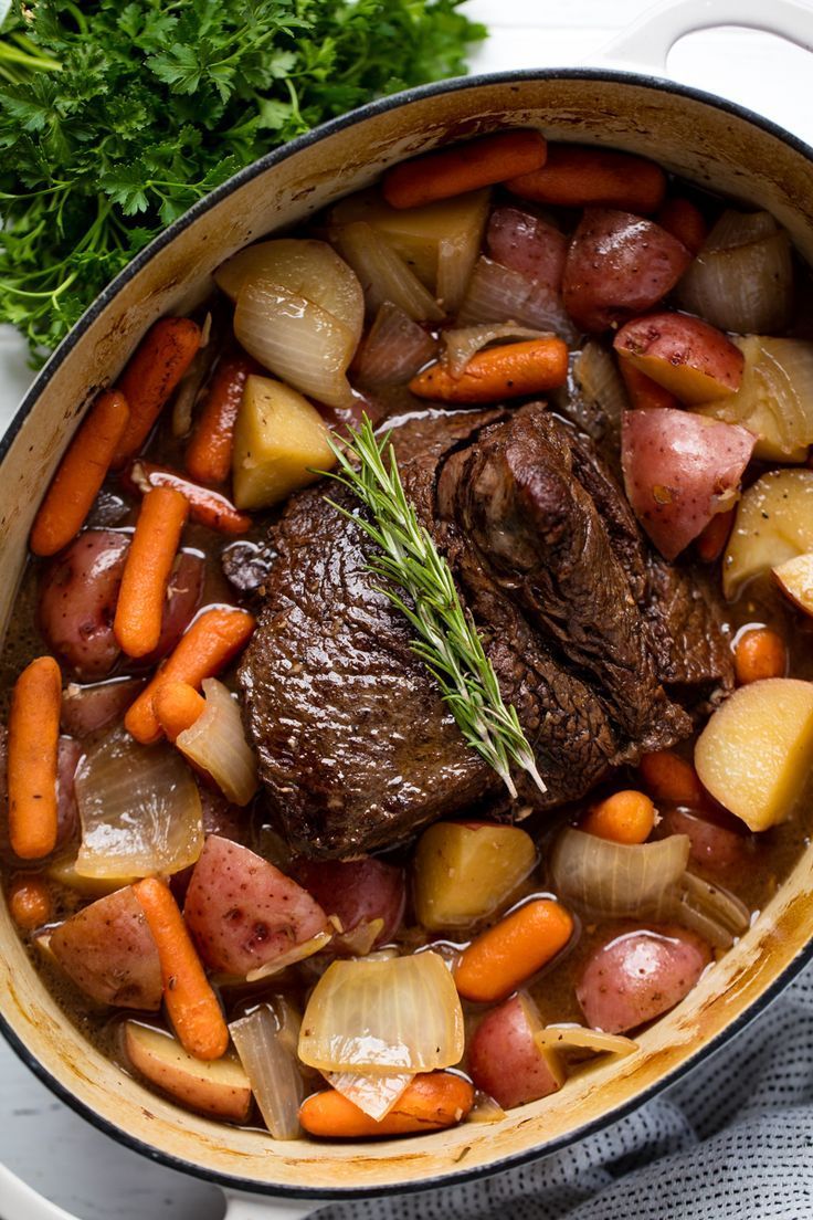 pot roast with carrots, potatoes and parsley in a pan on a table