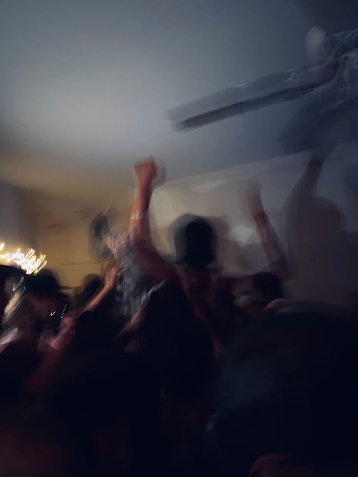 blurry photograph of people dancing in a room with lights on the ceiling and an airplane overhead