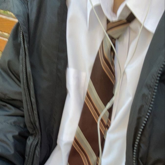 a man wearing a white shirt, brown striped tie and black jacket with zippers