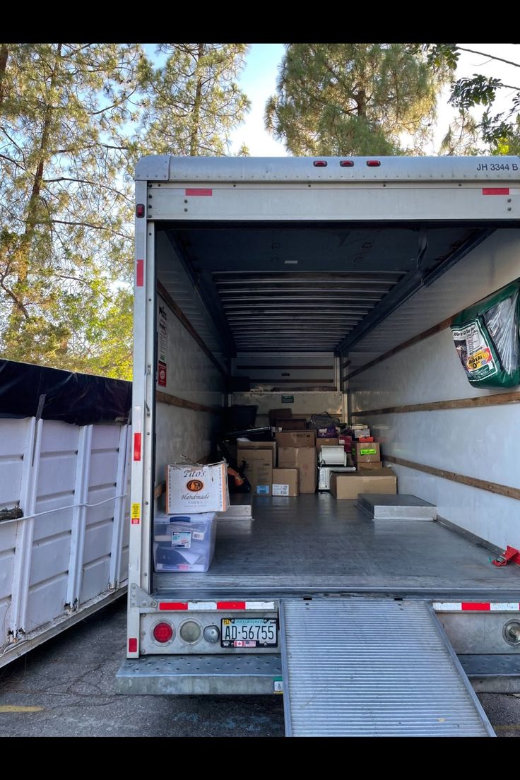 the back of a moving truck with its door open and boxes stacked in the back