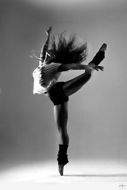 a woman is doing a handstand in the air with her hair flying through the air